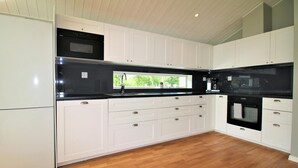 Une cuisine moderne avec des meubles blancs, un plan de travail noir et un plancher en bois.