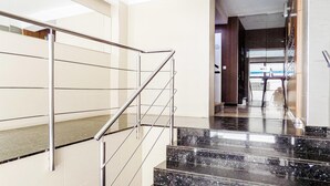 Et moderne interiør med trappe i metal og skakt til glas elevator.