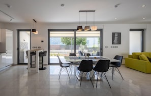 Una cucina moderna con zona pranzo, ampie finestre e un divano giallo.