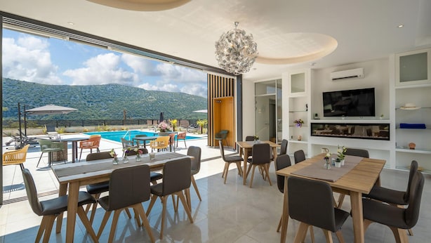 A modern dining area with a pool view, a chandelier, and a flat-screen TV. - Luxurious home in Grizane with sauna (Grizane)