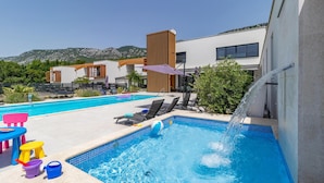 A swimming pool with a water feature, lounge chairs, and a children's play area with toys. - Luxurious home in Grizane with sauna (Grizane)