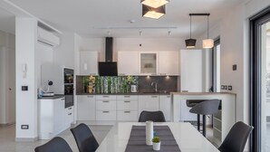 A modern kitchen with white cabinets, a central island, and pendant lighting. - Luxurious home in Grizane with sauna (Grizane)