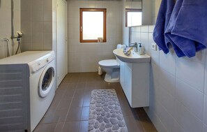 A compact bathroom with a washing machine, toilet, sink, and a window. - Nice home in Tyringe with WiFi (Tyringe)