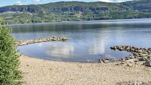 A lake with a rocky shoreline and a forested hill in the background. - Lovely home in Vikersund with sauna (Vikersund)