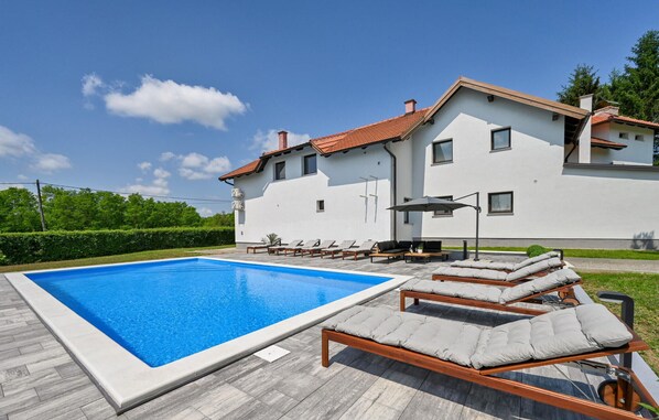 Une maison moderne dotée d’une piscine, d’un espace extérieur aménagé et d’un jardin bien entretenu.