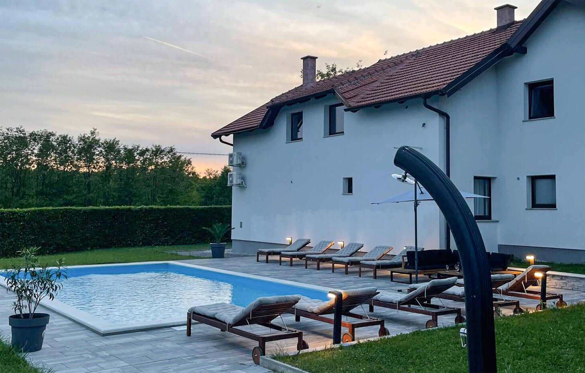Et hus med swimmingpool, liggestole og have.
