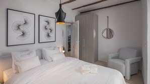 A modern bedroom with a large bed, a wardrobe, a chair, and two wall-mounted artworks. - Luxurious home in Cabrunici with sauna (Cabrunici)
