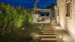 A stone building with a covered outdoor seating area and a gravel pathway leading to it. - Luxurious home in Cabrunici with sauna (Cabrunici)