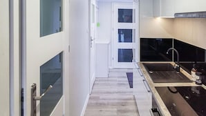 Une cuisine étroite au design moderne, avec une palette de couleurs en noir et blanc, un four encastré et un évier avec un robinet.