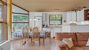 A modern kitchen with white cabinets, a dining area with wooden chairs and a table, and a cozy living area with a brown sofa. - Awesome home in Hals with kitchen (Hals)