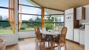 A modern kitchen with white cabinets, a dining table with chairs, and a view of the outdoors through large windows. - Awesome home in Hals with kitchen (Hals)