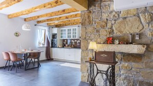 A kitchen with stone walls, wooden beams, a dining area with chairs, and a vintage sewing machine. - Gorgeous home in Zarecje with WiFi (Zarecje)