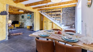 A dining area with a wooden table set for four, surrounded by brown chairs. A staircase with a stone wall on one side leads to another room. - Gorgeous home in Zarecje with WiFi (Zarecje)