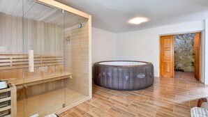 A sauna room with a wooden bench, a glass-enclosed shower area, and a stone wall. - Luxurious home in Rukljevina with sauna (Rukljevina)