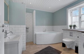 A bathroom with a bathtub, toilet, and sink, featuring white tiles and a light blue wall.