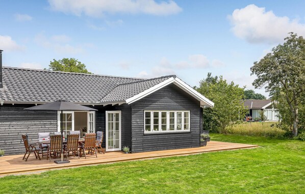 A modern house with a dark exterior, a tiled roof, and a wooden deck.