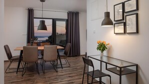 Ein moderner Essbereich mit Holztisch und Stühlen, einem Glastisch und Blick ins Freie.