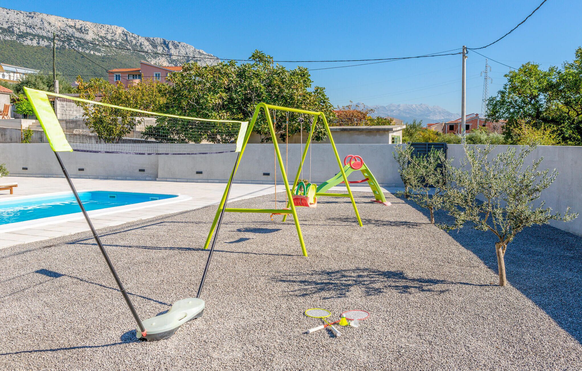A pool area with a swing set and a small tree.