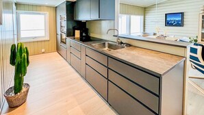 Une cuisine moderne dotée d’un îlot central, d’appareils électroménagers en acier inoxydable et d’une grande fenêtre.