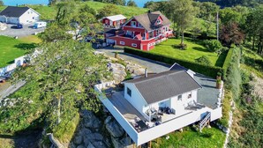 Une grande maison à deux étages, à la façade rouge et blanche, située près d’une étendue d’eau.