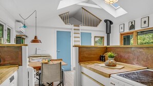 Une cuisine de taille réduite, dotée d’un plan de travail en bois, d’une cuisinière et d’une porte bleue.