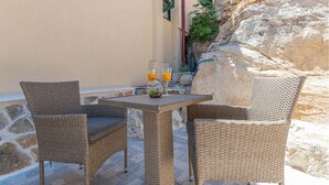 A wicker table with two chairs, a glass of orange juice, and a glass of water on a stone-paved patio. - 3 bedroom cozy home in Skradin (Skradin)