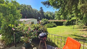 Un patio trasero con una parrilla, un cobertizo pequeño y una casa al fondo.