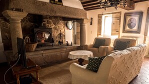 A cozy living room with a stone fireplace, a sofa with patterned cushions, and a television on a wooden stand.
