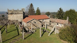 A stone building with a red-tiled roof, a stone tower, and a grassy courtyard.