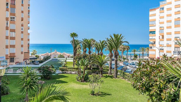 A beachfront hotel with multiple floors, a pool area, and palm trees. - Beautiful apartment with pool (Torrox-Costa)