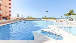 A swimming pool with multiple lanes, a lifeguard stand, and a view of the ocean. - Beautiful apartment with pool (Torrox-Costa)