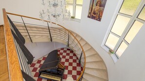 Una imponente escalera con piso a cuadros, un piano y una araña.
