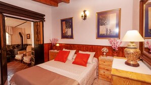 A bedroom with a bed, wooden headboard, two nightstands, a dresser, a mirror, and a wall-mounted lamp. - Nice home in Antequera (Antequera)