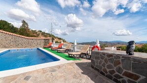 A pool area with stone walls, lounge chairs, and a view of the landscape. - Nice home in Antequera (Antequera)