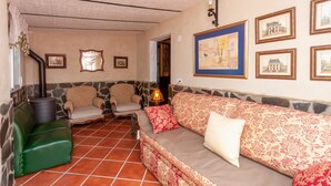 A cozy living room with a stone wall, a green sofa, patterned cushions, and a fireplace. - Nice home in Antequera (Antequera)