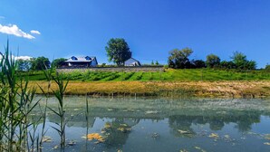 Ein Haus mit einer Steinmauer und einem Teich im Vordergrund.
