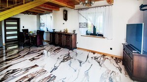 Ein großzügiger Wohnbereich mit Marmorboden, Holzmöbeln und einem Fernseher.