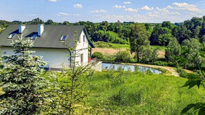 Ein modernes Gebäude mit geneigtem Dach und einem kleinen Teich im Vordergrund.