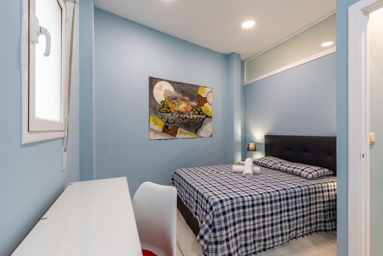 Una camera da letto con un letto, una scrivania e un quadro appeso al muro.