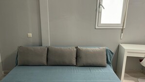Ein Schlafzimmer mit Bett, Kissen, Schreibtisch und Fenster.