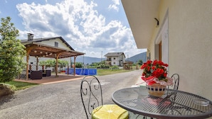 A patio area with a table and chairs, a covered seating area, and a view of houses and mountains in the background.