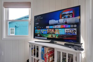 Ein Flachbildfernseher an einer weißen Unterhaltungsanlage, auf der ein Fernbedienung liegt.