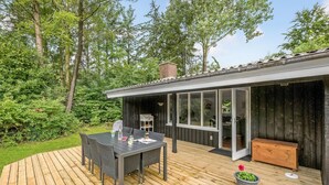 A deck with a table and chairs, a grill, and a wooden bench. - 3 bedroom gorgeous home in Oksbøl (Oksbøl)