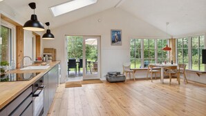 A spacious kitchen with wooden flooring, a dining area with natural light, and a view of the outdoors. - Awesome home in Nykøbing Sj with WiFi (Nykøbing Sj)