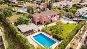 A residential property with a swimming pool, a covered patio, and a well-maintained garden.