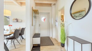 Un interior modern amb una zona de menjador, un passadís que condueix a un dormitori i un mirall gran a la paret.