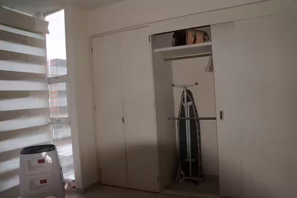 Habitación con armario grande, una escalera y una ventana con persianas.