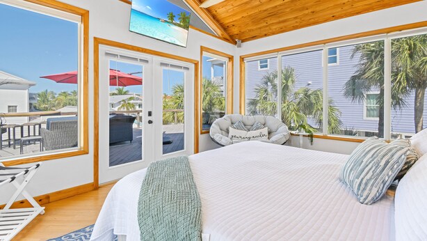 A bedroom with a large bed, a ceiling fan, and a view of the ocean through large windows. - Private POOL/SPA-Almost beachfront, Amazing Gulf Views, walk to Bridge St. (Bradenton Beach)