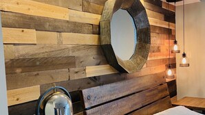 A bedroom with a wooden headboard, a round mirror, bedside lamps, and a bed with pillows. - Raleigh's famous mushroom house (Raleigh)