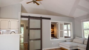 A modern kitchen with white cabinets, a wooden floor, a sliding glass door, and a ceiling fan. - Raleigh's famous mushroom house (Raleigh)